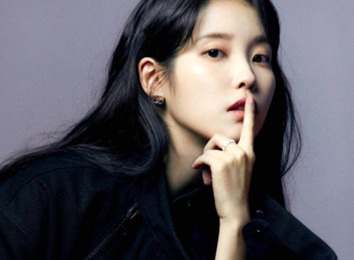 Korean singer and actress IU posing with her finger on her lips.