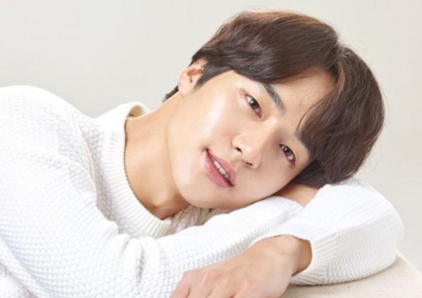 Korean actor Mr. Yang posing in white shirt, with head resting on his arm.