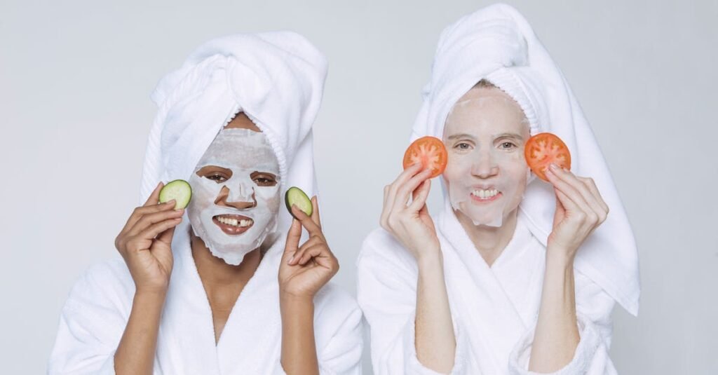 Optimistic multiethnic females wearing towels and bathrobes applying slices of cucumbers and tomatoes for skincare moisturizing treatment