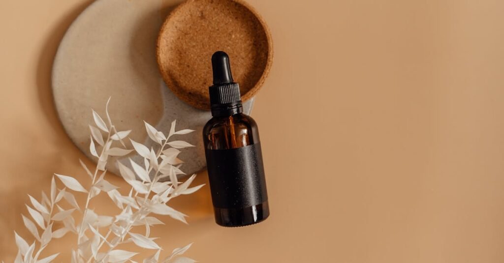 A minimalist skincare bottle with a dropper in a flat lay on a neutral background, surrounded by dried leaves.