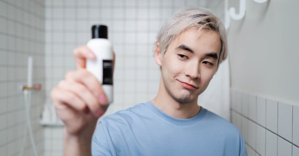 Portrait of a young man showcasing a skincare product in a modern bathroom setting.