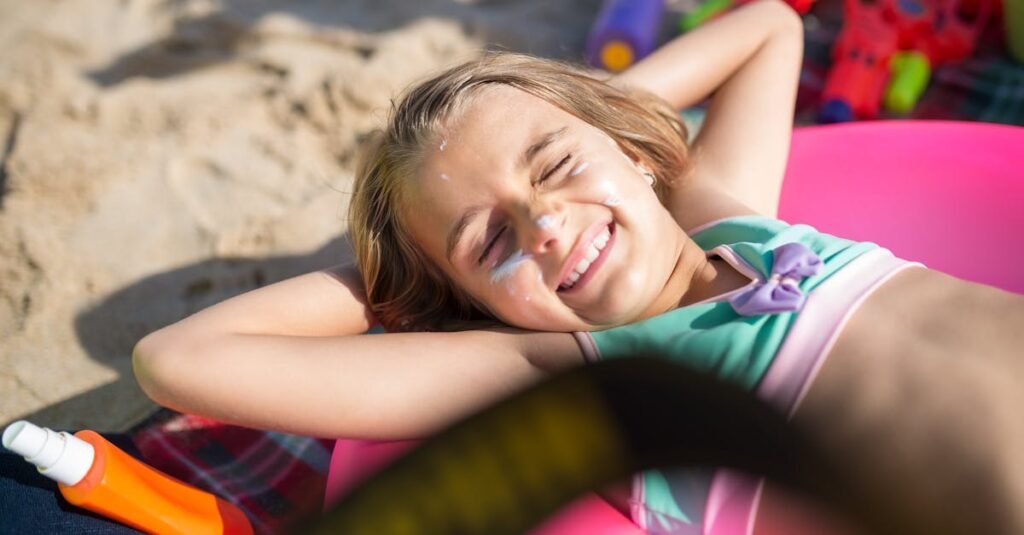 A happy young girl with sunscreen, sunbathing on a beach in Portugal during a sunny summer day.